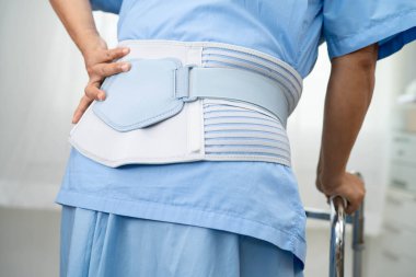 Ortopedik bel kemiği için sırt ağrısı destek kemeri takan Asyalı bir kadın hasta..