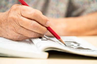 Alzheimer Hastalığı AD, Asyalı yaşlı kadın sudoku bulmaca oyunu oynuyor.