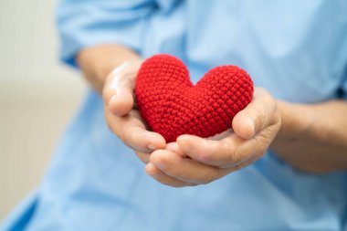 Asian doctor give red heart to elderly woman in her hand, heart Attack. clipart