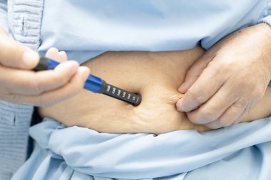 Diyabet tedavisi için karnına insülin iğnesi yapan Asyalı son sınıf öğrencisi kadın..