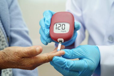 Diyabet tedavisinde kan şekeri seviyesini kontrol etmek için dijital glikoz ölçer kullanan Asyalı doktor.