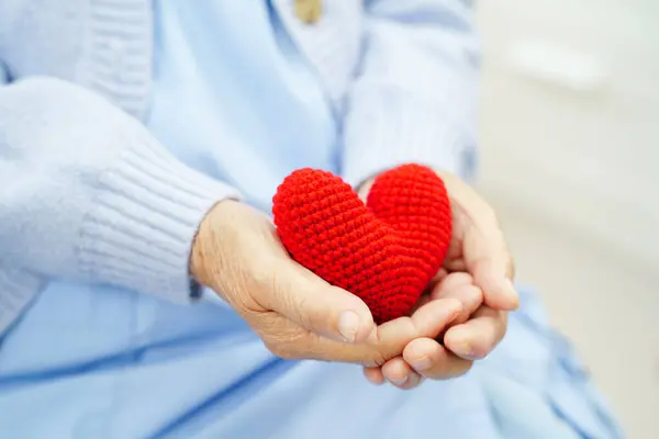 Hastanede kalbi kırmızı olan Asyalı yaşlı bir kadın..