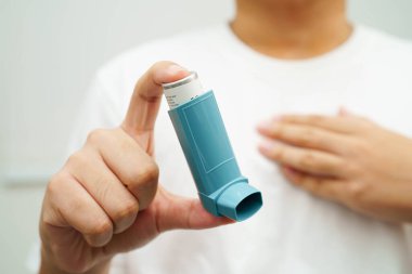 Astım ve kronik obstrüktif akciğer hastalığı COPD, Asyalı genç adam ölçülü doz solunum cihazı kullanıyor..