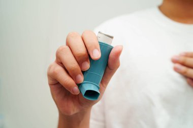 Astım ve kronik obstrüktif akciğer hastalığı COPD, Asyalı genç adam ölçülü doz solunum cihazı kullanıyor..