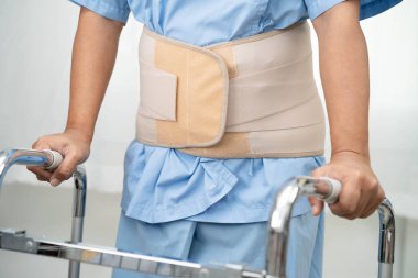 Asya baş ağrısı. Esnek destek kemeri takıp yürüteç takıyor..