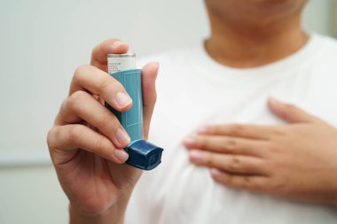 Astım ve kronik obstrüktif akciğer hastalığı COPD, Asyalı genç adam ölçülü doz solunum cihazı kullanıyor..