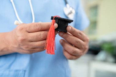 Hastanede elinde mezuniyet şapkası olan Asyalı kadın doktor. Tıp eğitimi konsepti..
