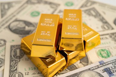 Gold bars on US dollar banknote money, finance trading investment business currency concept.