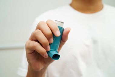 Astım ve kronik obstrüktif akciğer hastalığı COPD, Asyalı genç adam ölçülü doz solunum cihazı kullanıyor..