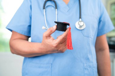 Hastanede elinde mezuniyet şapkası olan Asyalı kadın doktor. Tıp eğitimi konsepti..