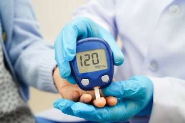 Diyabet tedavisinde kan şekeri seviyesini kontrol etmek için dijital glikoz ölçer kullanan Asyalı doktor.