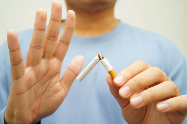 Бросить курить, азиат сломать уничтожить сигарету в руке.