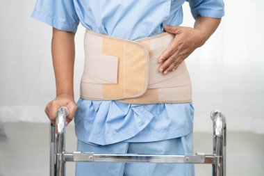 Asya baş ağrısı. Esnek destek kemeri takıp yürüteç takıyor..