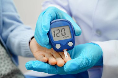 Diyabet tedavisinde kan şekeri seviyesini kontrol etmek için dijital glikoz ölçer kullanan Asyalı doktor.