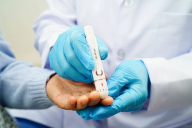 Diyabet tedavisinde kan şekeri seviyesini kontrol etmek için dijital glikoz ölçer kullanan Asyalı doktor.