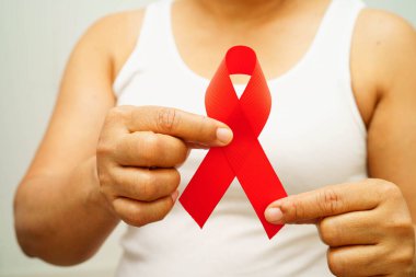 Aralık ayı AIDS günü için kırmızı kurdeleli Asyalı kadın. AIDS ve HIV farkındalığı.