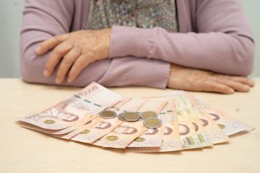 Emekli Asyalı yaşlı kadın para sayıyor ve aylık giderleri ve tedavi ücretini düşünüyor.