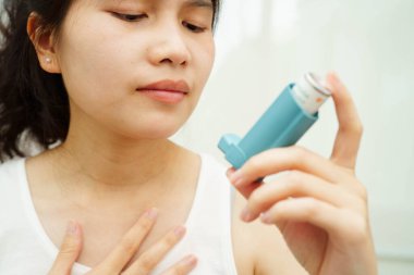 Astım ve kronik obstrüktif akciğer hastalığı KOAH, Asyalı genç ölçülü doz solunum cihazı kullanıyor..