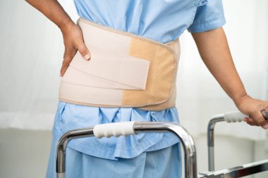 Asya baş ağrısı. Esnek destek kemeri takıp yürüteç takıyor..