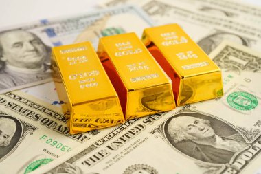 Gold bars on US dollar banknote money, finance trading investment business currency concept.