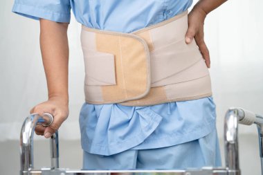 Asya baş ağrısı. Esnek destek kemeri takıp yürüteç takıyor..