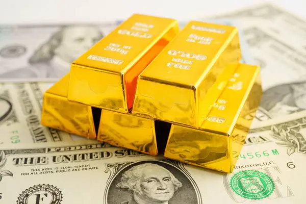 Gold bars on US dollar banknote money, finance trading investment business currency concept.
