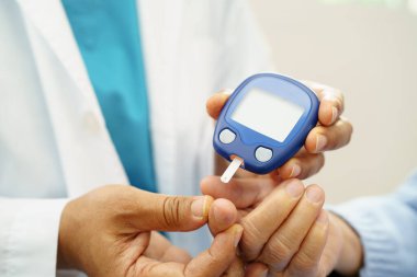 Diyabet tedavisinde kan şekeri seviyesini kontrol etmek için dijital glikoz ölçer kullanan Asyalı doktor.