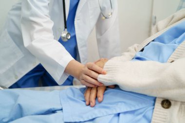 Asyalı doktor yaşlı kadın hasta sağlığını hastanede kontrol edip tedavi ediyor.