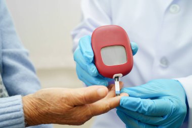 Diyabet tedavisinde kan şekeri seviyesini kontrol etmek için dijital glikoz ölçer kullanan Asyalı doktor.