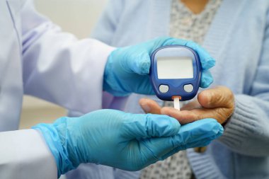 Diyabet tedavisinde kan şekeri seviyesini kontrol etmek için dijital glikoz ölçer kullanan Asyalı doktor.