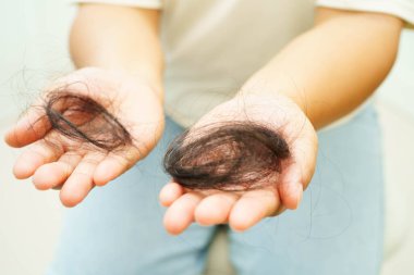Asian woman have problem with long hair loss attach in her hand.