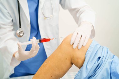 Asyalı doktor yaşlı kadının dizine Hyaluronic asit trombosit enjekte ediyor..