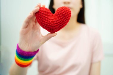 Gökkuşağı bayrağıyla LGBT kalbini tutan Asyalı kadın.