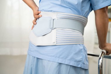 Asya baş ağrısı. Esnek destek kemeri takıp yürüteç takıyor..