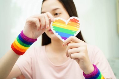 Gökkuşağı bayrağıyla LGBT kalbini tutan Asyalı kadın.
