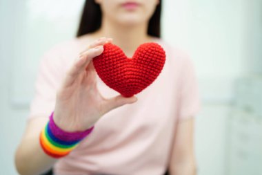 Gökkuşağı bayrağıyla LGBT kalbini tutan Asyalı kadın.