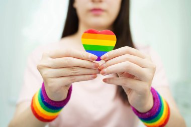 Gökkuşağı bayrağıyla LGBT kalbini tutan Asyalı kadın.
