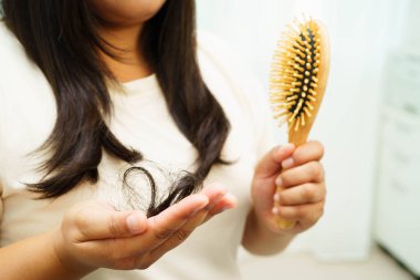 Asian woman have problem with long hair loss attach in her hand.