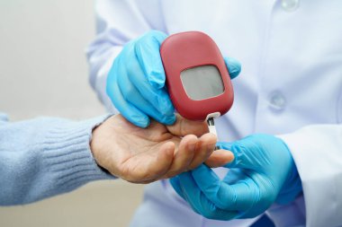 Diyabet tedavisinde kan şekeri seviyesini kontrol etmek için dijital glikoz ölçer kullanan Asyalı doktor.