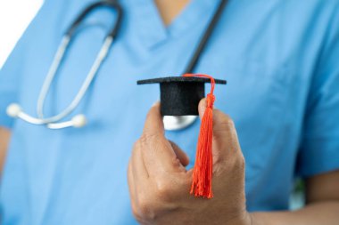 Asyalı doktor mezuniyet şapkası ve eğitim ilacı taşıyor..