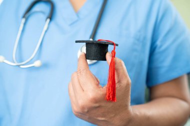 Asyalı doktor mezuniyet şapkası ve eğitim ilacı taşıyor..