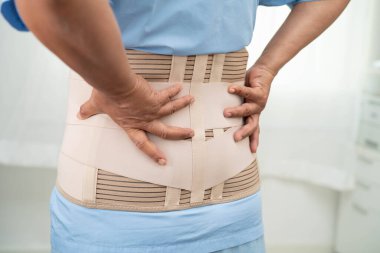 Asya baş ağrısı. Esnek destek kemeri takıp yürüteç takıyor..