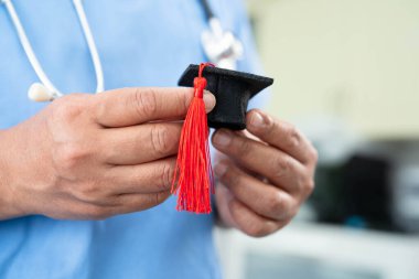 Hastanede elinde mezuniyet şapkası olan Asyalı kadın doktor. Tıp eğitimi konsepti..
