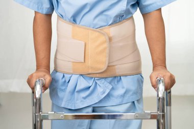 Asya baş ağrısı. Esnek destek kemeri takıp yürüteç takıyor..