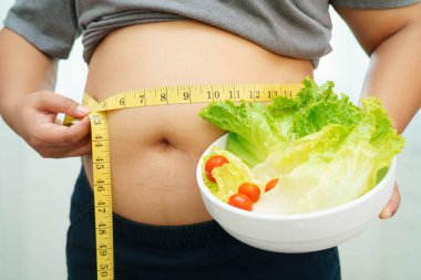 Koca göbekli, şişman, kilolu ve sağlıklı yiyecekleri olan Asyalı bir kadın..