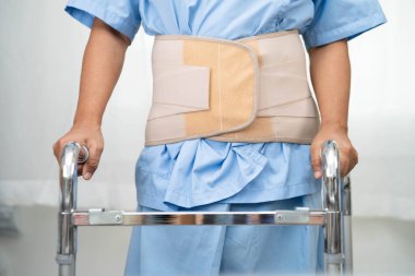 Asya baş ağrısı. Esnek destek kemeri takıp yürüteç takıyor..