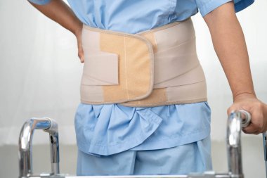 Asya baş ağrısı. Esnek destek kemeri takıp yürüteç takıyor..