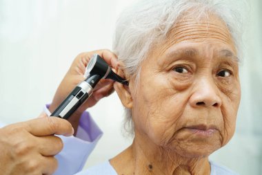 Otolaryngologist ya da ENT hekim doktoru yaşlı hasta kulağını otoskopla muayene ediyor, işitme sorunu var..