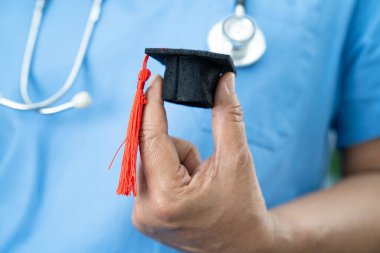 Hastanede elinde mezuniyet şapkası olan Asyalı kadın doktor. Tıp eğitimi konsepti..