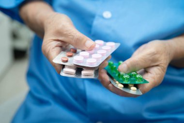 Asyalı yaşlı kadın elinde hap tutuyor, güçlü sağlıklı tıbbi konsept..